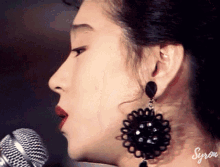 a close up of a woman singing into a microphone with syron written on the bottom right