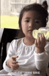a little girl is sitting in a chair eating a slice of apple .
