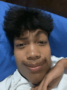 a young man is laying on a bed with a blue pillow