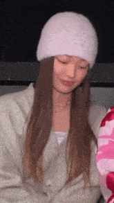 a woman wearing a pink beanie and a grey sweater