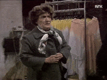 a woman is standing in front of a rack of clothes with the letters nrk on the bottom