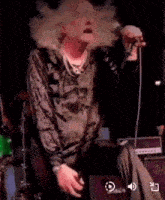 a man with a mustache is singing into a microphone on stage