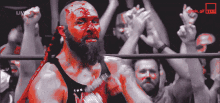 a man with blood on his face stands in front of a crowd with the words live on the bottom right