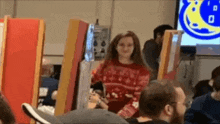 a woman in a red sweater is standing in front of a crowd of people .