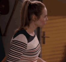 a woman wearing a striped sweater is standing in front of a door .