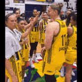a group of female basketball players wearing yellow jerseys with the number 11 on the back