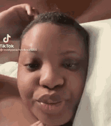 a woman is laying in bed with a pillow on her head and making a funny face .
