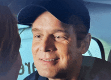 a man wearing a baseball cap is smiling in front of a sign that says 911