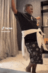 a man in a black shirt and white shorts is dancing in a living room .