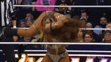 a woman is in a wrestling ring with a referee behind her
