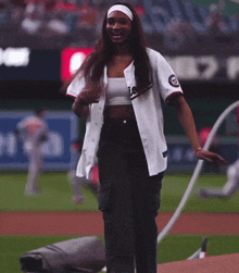 a woman wearing a nationals jersey stands on the field
