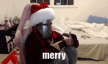 a person wearing a santa hat is sitting in a chair and says merry