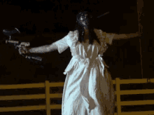 a woman in a white dress is standing in front of a yellow fence