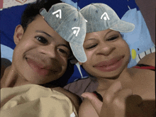 a man and a woman are laying on a bed with hats on their faces with the letter a on them