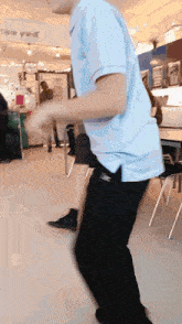 a man in a blue shirt is dancing in front of a sign that says " captain grande "