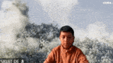 a young boy is sitting in front of a cloudy sky with a luma logo in the corner