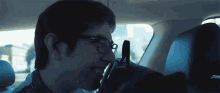 a man wearing glasses is sitting in the back seat of a vehicle