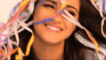 a woman is smiling while holding a bunch of ribbons in her hair .