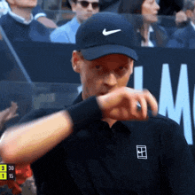 a man wearing a black nike hat looks at his wrist watch