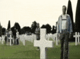 a man walking in a cemetery with a cross in the middle