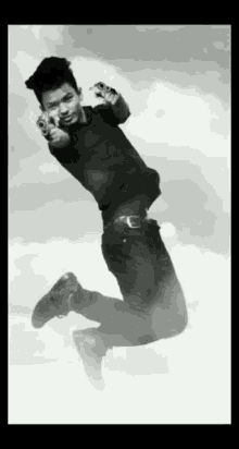 a man in a black shirt is jumping in the air with two guns pointing at the camera