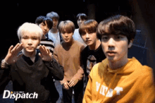 a group of young men are posing for a picture and one of them is wearing a yellow hoodie that says dispatch on it .