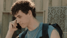 a young man with curly hair is talking on a cellphone