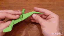 a person is holding a green origami dragon made by animatica