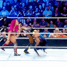 a woman with pink hair is wrestling another woman in a ring