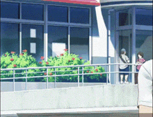 a couple of people standing outside of a building with flowers in the background