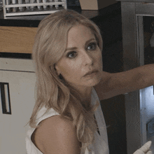 a woman in a white tank top is standing in front of a refrigerator