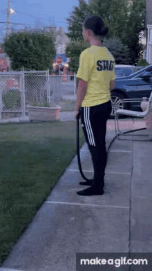 a girl wearing a yellow shirt that says staff is standing on a sidewalk