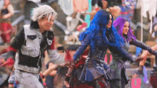 a group of people are dancing together in a crowd while one of them has blue hair .