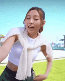 a woman wearing a white crop top and a white scarf around her shoulder