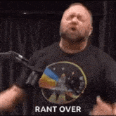 a man in a black t-shirt is standing in front of a microphone and saying `` rant over '' .