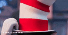 a cartoon cat in a red and white striped hat with #thecatinthehat written below it