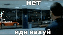 a man standing in front of a building with a car in the window and the words het in white