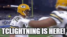 a football player wearing a green bay packers helmet is talking to another player on the field .