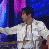 a man in a white jacket stands in front of a microphone with the word eh written on it