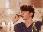 a young man is smoking a cigar at a table with candles .
