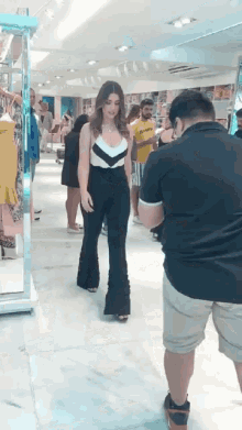 a man in a black shirt is taking a picture of a woman in a store