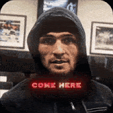 a man in a hooded jacket with the words come here above his head