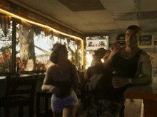 a man and a woman are standing in a restaurant with a sign that says burgers