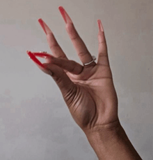 a woman 's hand with long red nails and a diamond ring