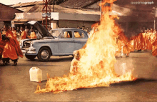 a group of monks are standing around a car on fire