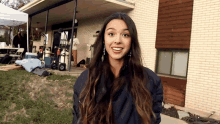 a woman with long hair is smiling in front of a brick house .