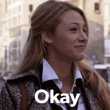 a woman wearing a coat and tie is smiling with the word okay below her