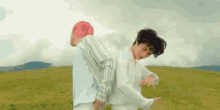 two young men are standing back to back in a field .