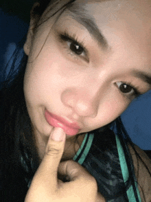 a close up of a girl 's face with her finger on her lips