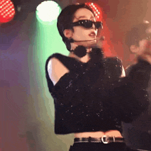 a woman wearing sunglasses and a crop top is dancing on stage